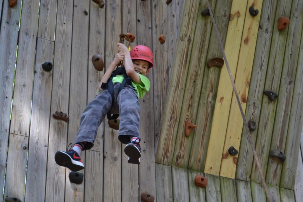 Young boy hanging from rappeling rope on climbing wall