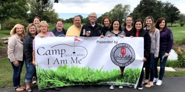 Group holding up banner sign for Camp I Am Me Golf Classic