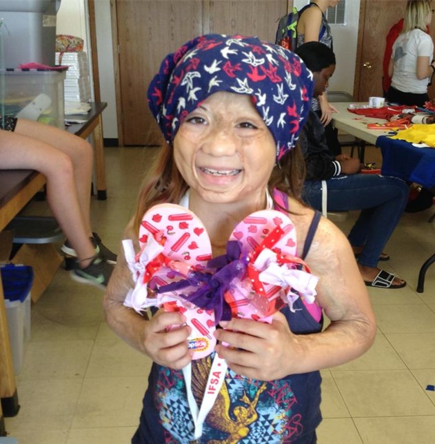 Young smiling girl poses with her flip flops