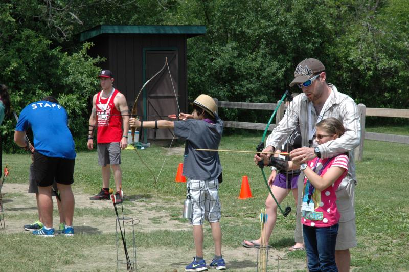 Young girl being taught archery by a camp instructor