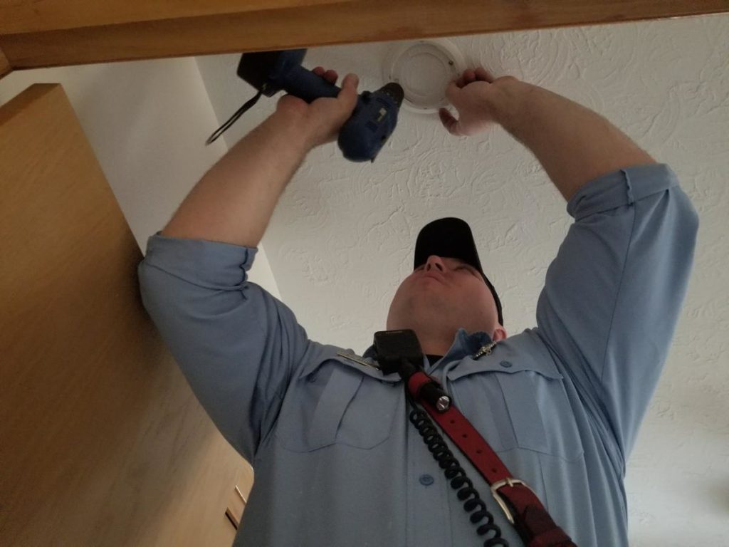 Technician installing a smoke alarm on ceiling