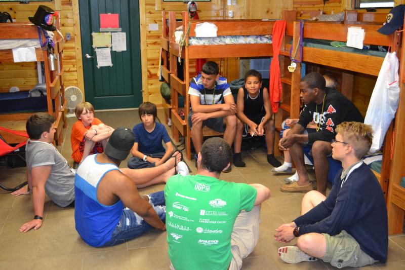 Young boys seated ina circle, hanging out in a cabin at camp