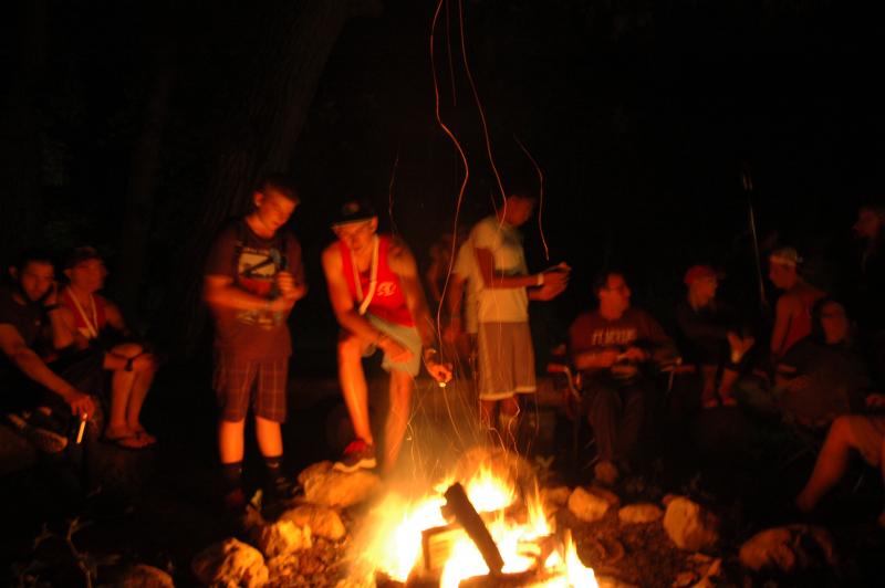 Campers gathered around a campfire at night