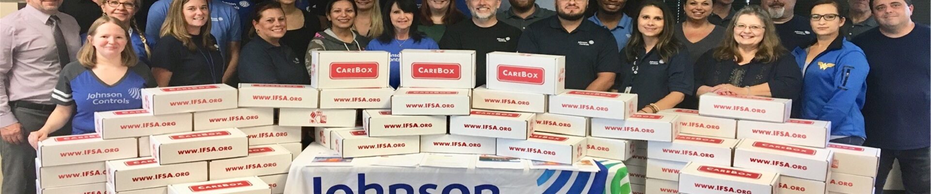 Johnson Controls volunteers pose with piles of CareBoxes