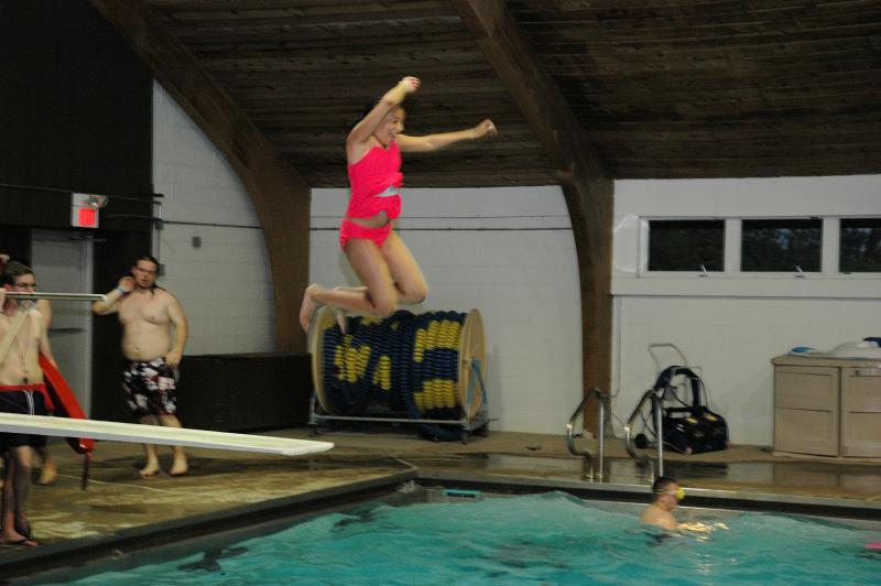 camper jumping off a diving board into an indoor pool