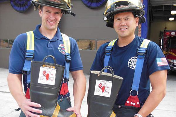 Two firefighters holding boots for donations