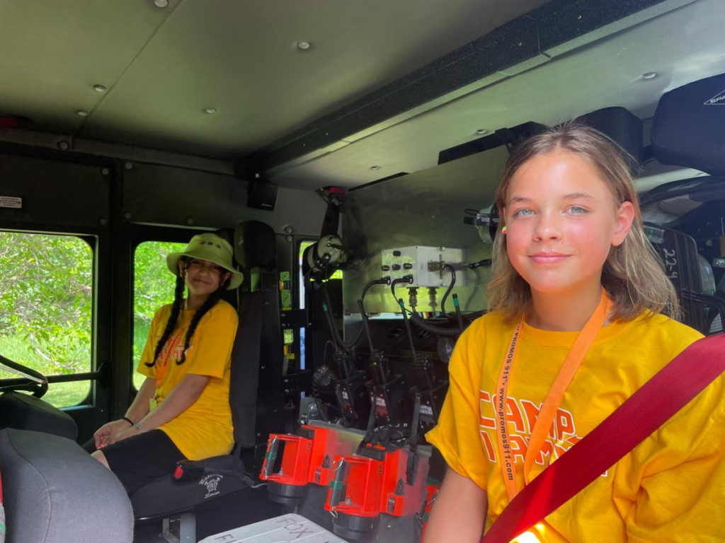 Young girl with Camp I Am Me shirt volunteering at the Fire Apparatus Parade